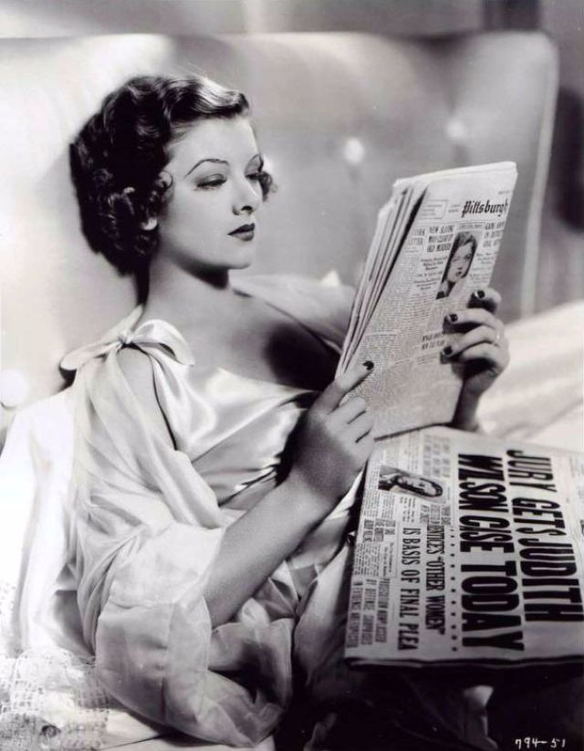 Myrna Loy reading a newspaper